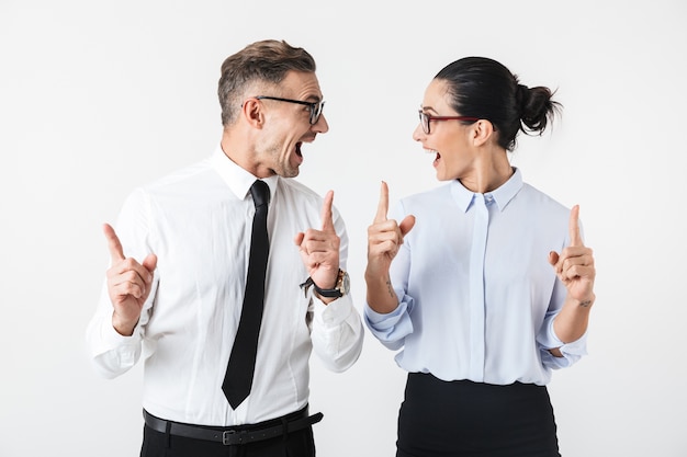 Image of young happy business colleagues couple isolated over white wall pointing.