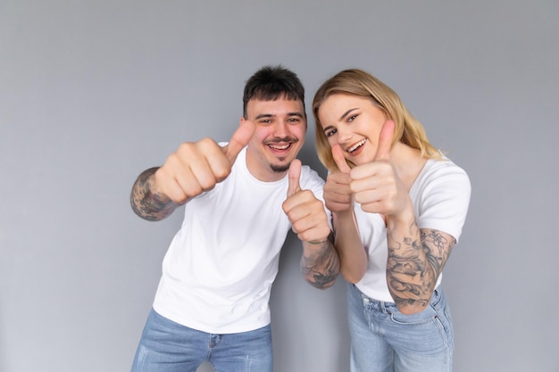 Image of young happy man kissing and hugging beautiful woman while taking selfie photo on gray wall