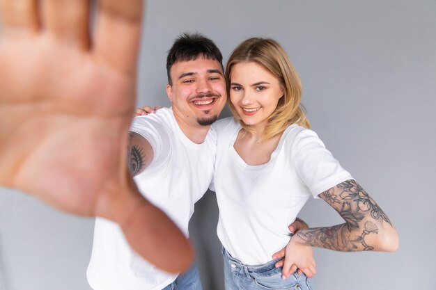 Image of young happy man kissing and hugging beautiful woman while taking selfie photo on gray wall