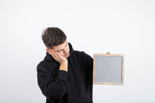 Image of young man in black hoodie holding empty frame