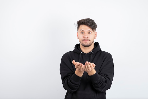 Image of young man in black hoodie standing and posing