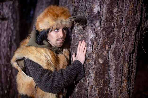 Image of a young man in a fox fur hat in the forest