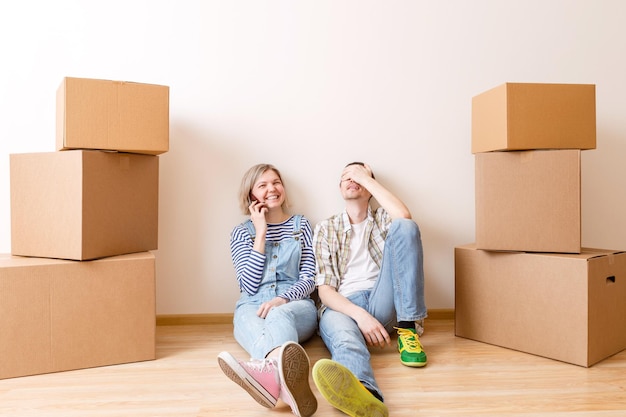 Image of young married couple sitting on floor among cardboard boxes