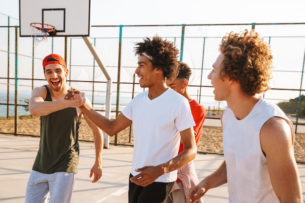 Photo image of young men basketball players standing at the playground outdoor, during summer sunny day