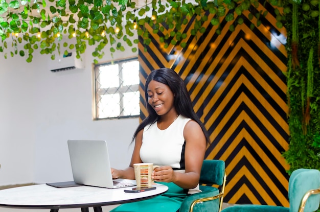 image of young office lady using laptop and holding coffee mug