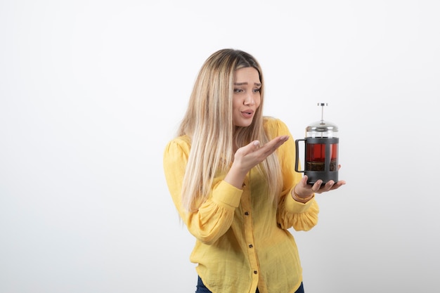 Image of a young pretty woman model holding a teapot .