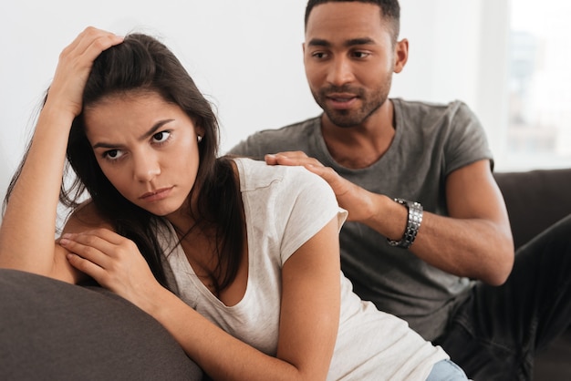 Photo image of young sad couple quarreling while sitting on sofa.