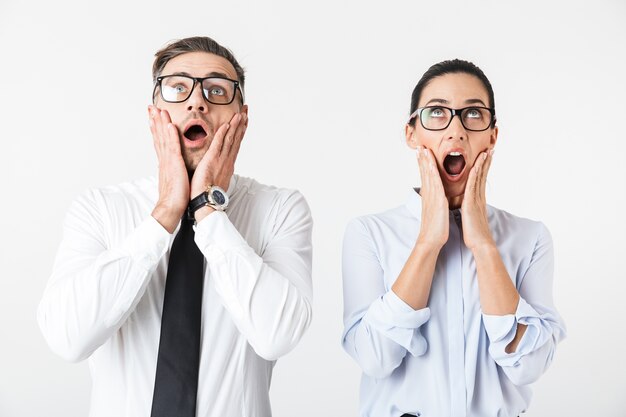 Image of young shocked business colleagues couple isolated over white wall.