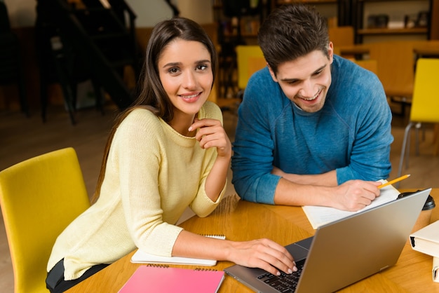 Image of a young students friends couple in library doing homework studying read and using laptop computer.