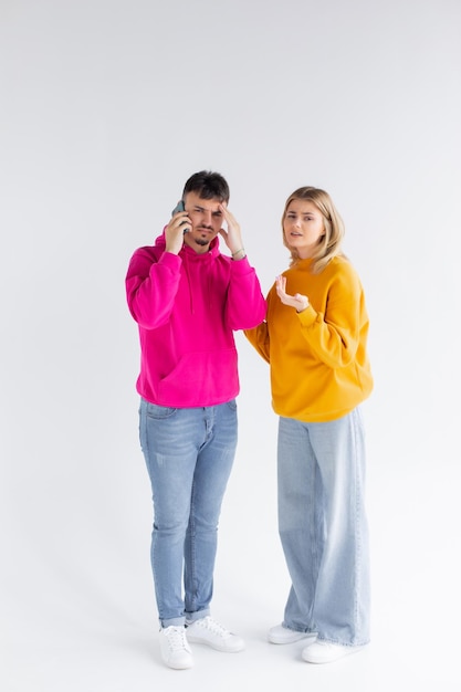 Image of young woman spying and peeking at cellphone of her boyfriend isolated over white