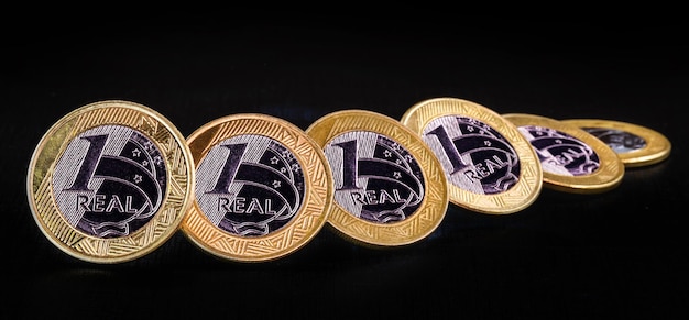 Images of one real coins money from brazil on isolated black background Falling real of the Brazilian real stock exchange loss