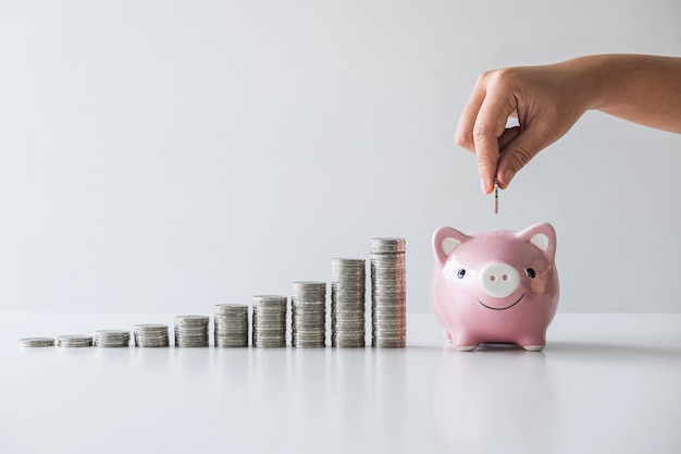 Images of stacking coins pile and Hand putting coin into pink piggy bank for planning step up to growing and savings with money box, Saving money for future plan and retirement fund 