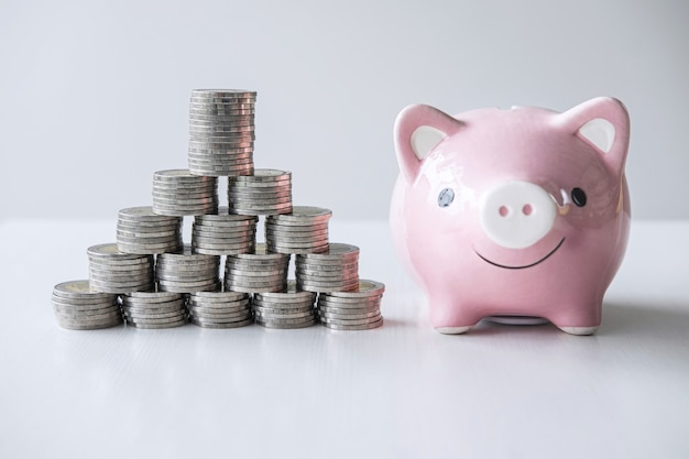 Images of stacking coins pile and pink smiling piggy bank to growing and savings with money box, Saving money for future plan and retirement fund concept