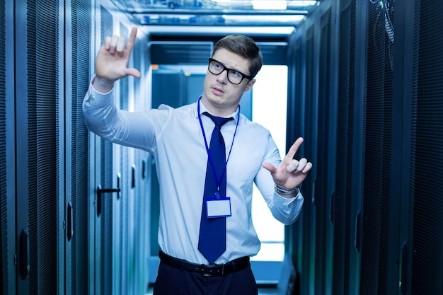 Imagination. Concentrated meditative operator standing near the server cabinets and imagining