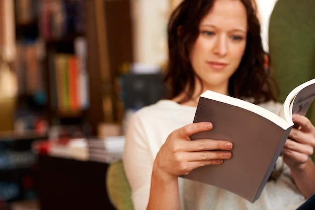 Immersed in the words A young woman quietly reading a book while seated in a chair