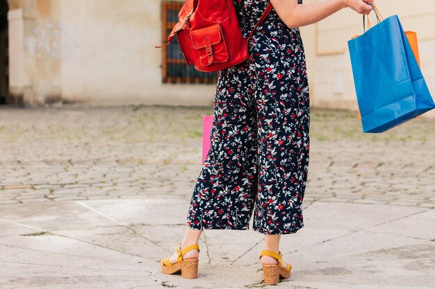 Foto impersonale le gambe di una donna dello shopping con borse colorate in mano. vista posteriore.