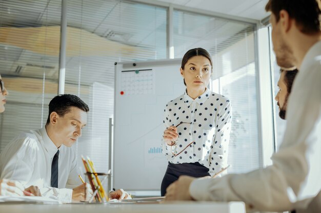 Important staff survey. Pleasant female boss conducting a daily meeting with her colleagues and listening to their feedback related to the changes in the contract