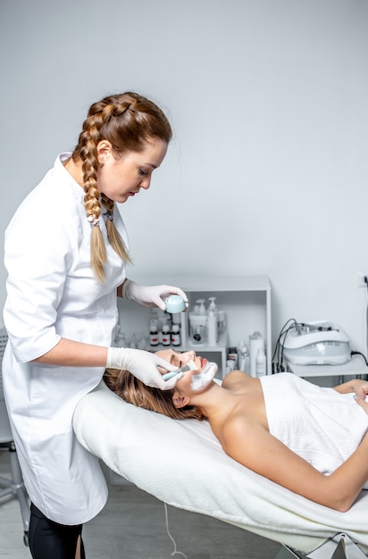 the imposition of a cosmetic mask on the face. a cosmetologist-dermatologist in a cosmetic clinic.