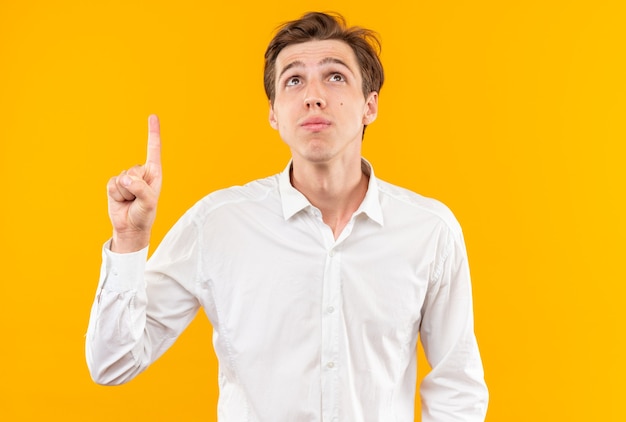 Impressed looking up young handsome guy wearing white shirt points at up 