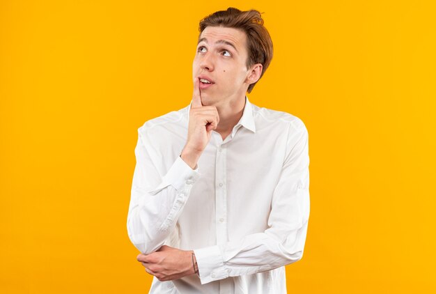 Impressed looking up young handsome guy wearing white shirt putting finger on chin 