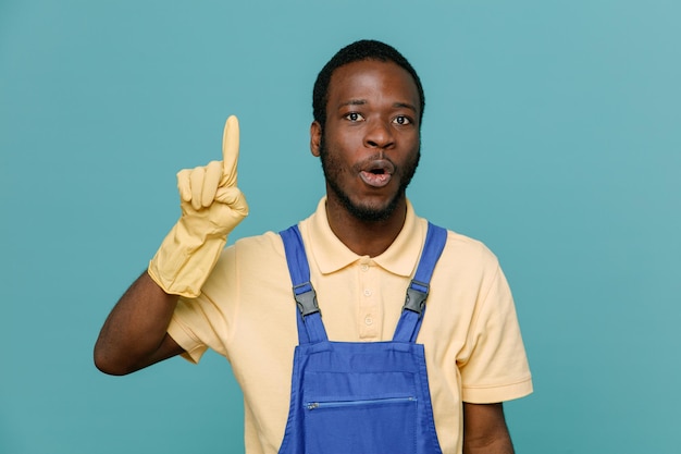 Punti impressionati su un giovane maschio pulitore afroamericano in uniforme con guanti isolati su sfondo blu