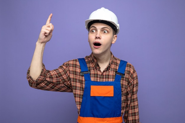 Impressed points at up young male builder wearing uniform 