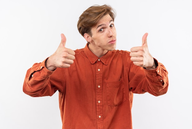 Impressionato testa inclinata giovane bel ragazzo che indossa una camicia rossa che mostra i pollici in su