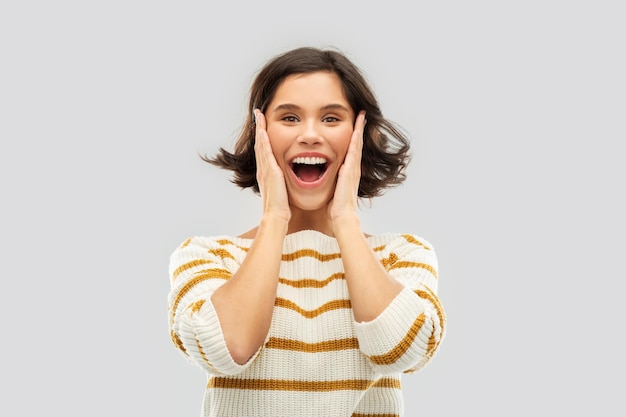 impressed woman in pullover holding to her face