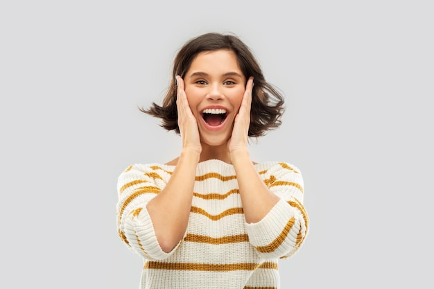 Photo impressed woman in pullover holding to her face