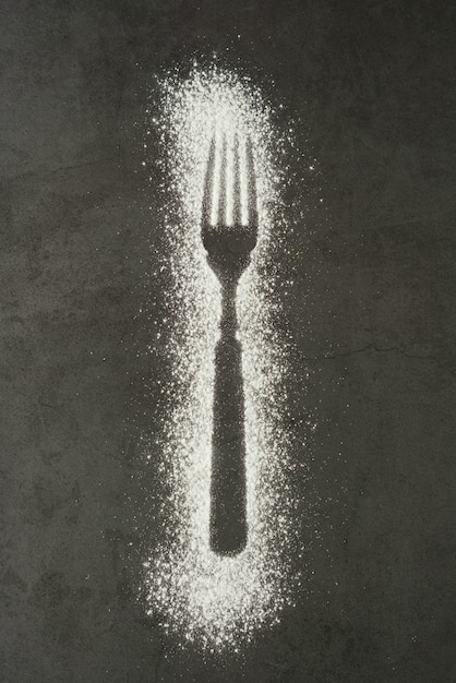 Imprint fork silhouette made of flour on a black background