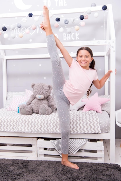 Improve flexibility girl child split in bedroom kid prepare go to bed girl cute pajamas relaxing and stretching stretching good evening stretching cute gymnast practice split before bedtime