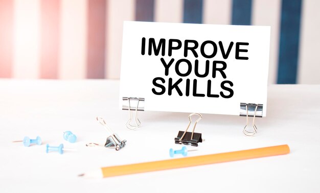 IMPROVE YOUR SKILLS sign on paper on white desk with office tools Blue and white background