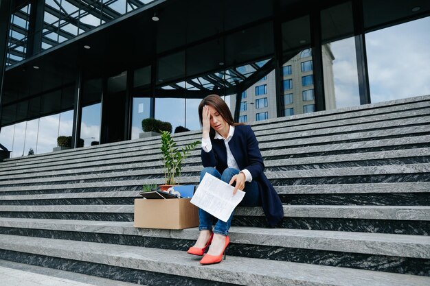 写真 失業と失業の強力な視覚的な表現で中年女性が階段に座って描かれています 悩みと悲しみの表情で困難と心配を体現しています