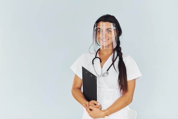 In beschermend gezichtsmasker Jonge vrouwelijke arts in uniform is binnenshuis