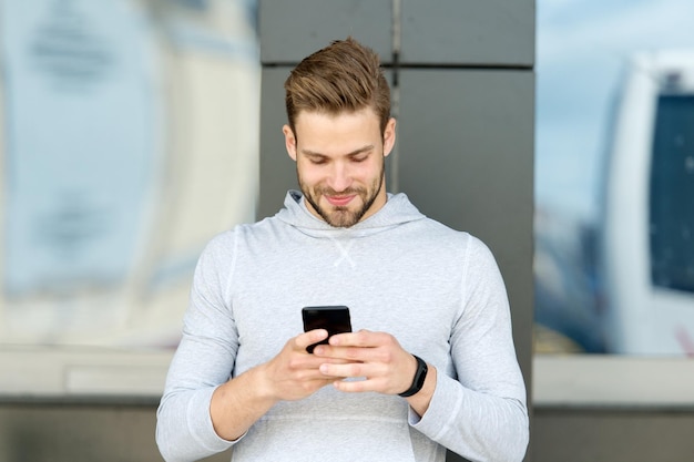 In contact blijven Man met baard loopt met smartphone stedelijke achtergrond Guy gebruikt smartphone om bericht te verzenden in contact blijven Man typen SMS-smartphone Stuur bericht concept