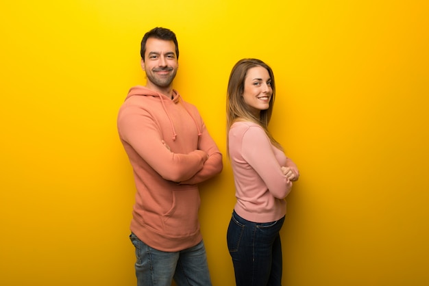 In dag van de Valentijnskaart Groep van twee mensen op gele achtergrond houden de armen gekruist in zij positie tijdens het glimlachen