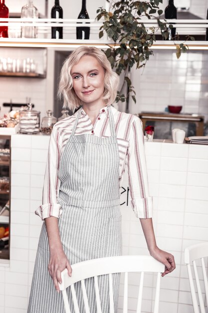 In de bakkerij. Mooie blonde vrouw permanent in de buurt van de stoel tijdens het werken in de bakkerij