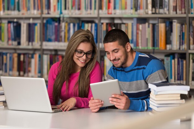 In de bibliotheek knappe twee studenten met laptop en boeken werken in een middelbare school Universiteitsbibliotheek ondiepe scherptediepte