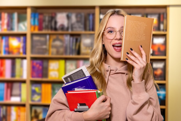 In de bibliotheek. Mooie blonde vrouw die zich met boeken in bibliotheek bevindt