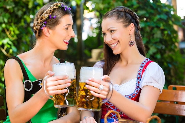 In de biertuin - vriendinnen in Tracht, Dirndl en Lederhosen drinken een vers biertje in Beieren, Duitsland