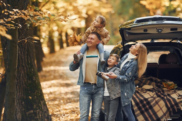 In de buurt van auto met open kofferbak Gelukkige familie is in de herfst samen in het park