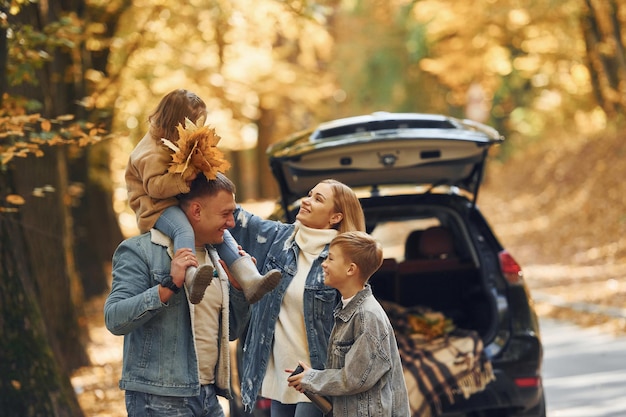 In de buurt van auto met open kofferbak Gelukkige familie is in de herfst samen in het park