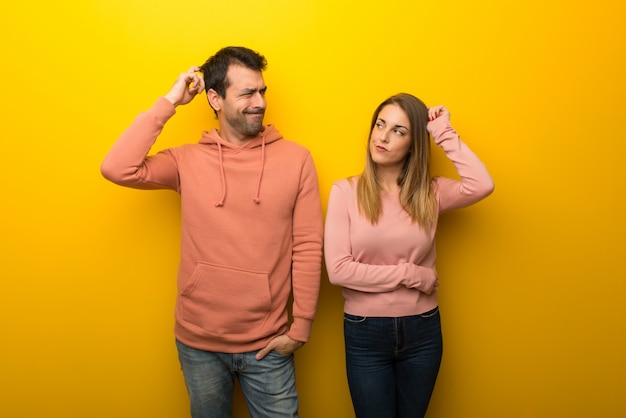 In de dag van de valentijnskaart groep van twee mensen op gele achtergrond twijfels terwijl hoofd krabben