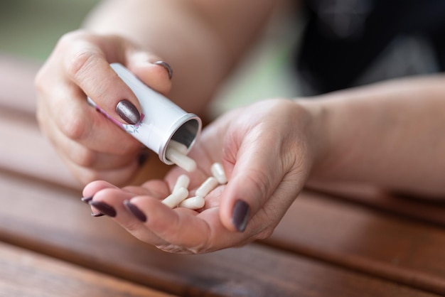 In de handen van een vrouw een handvol capsules met medicijnen en een lege pot van deze medicijnen