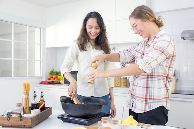 In de keuken bereiden twee gelukkige jonge tweelingzussen spaghetti voor de lunch.