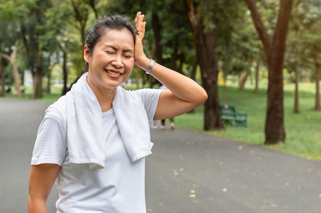 In de ochtend. Senior vrouw Aziatische hoofdpijn tijdens het sporten in het park.
