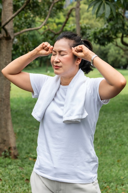 In de ochtend. Senior vrouw Aziatische hoofdpijn tijdens het sporten in het park.