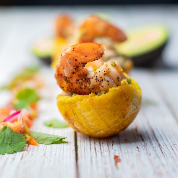 In de pan aangebraden garnalen met een bakbanaan mand met guacamole