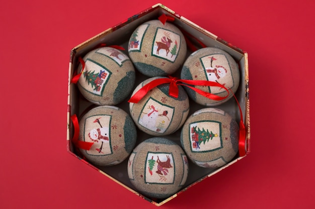 In de vakantievak staan verschillende vintage kerstboomballen op een rode papieren achtergrond.