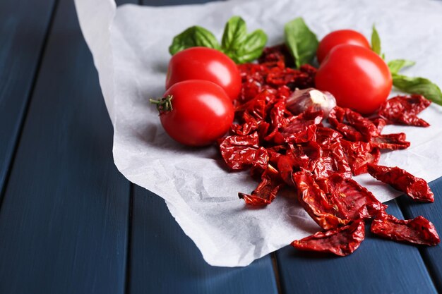 In de zon gedroogde en verse tomaten basilicum bladeren knoflook op een houten achtergrond kleur